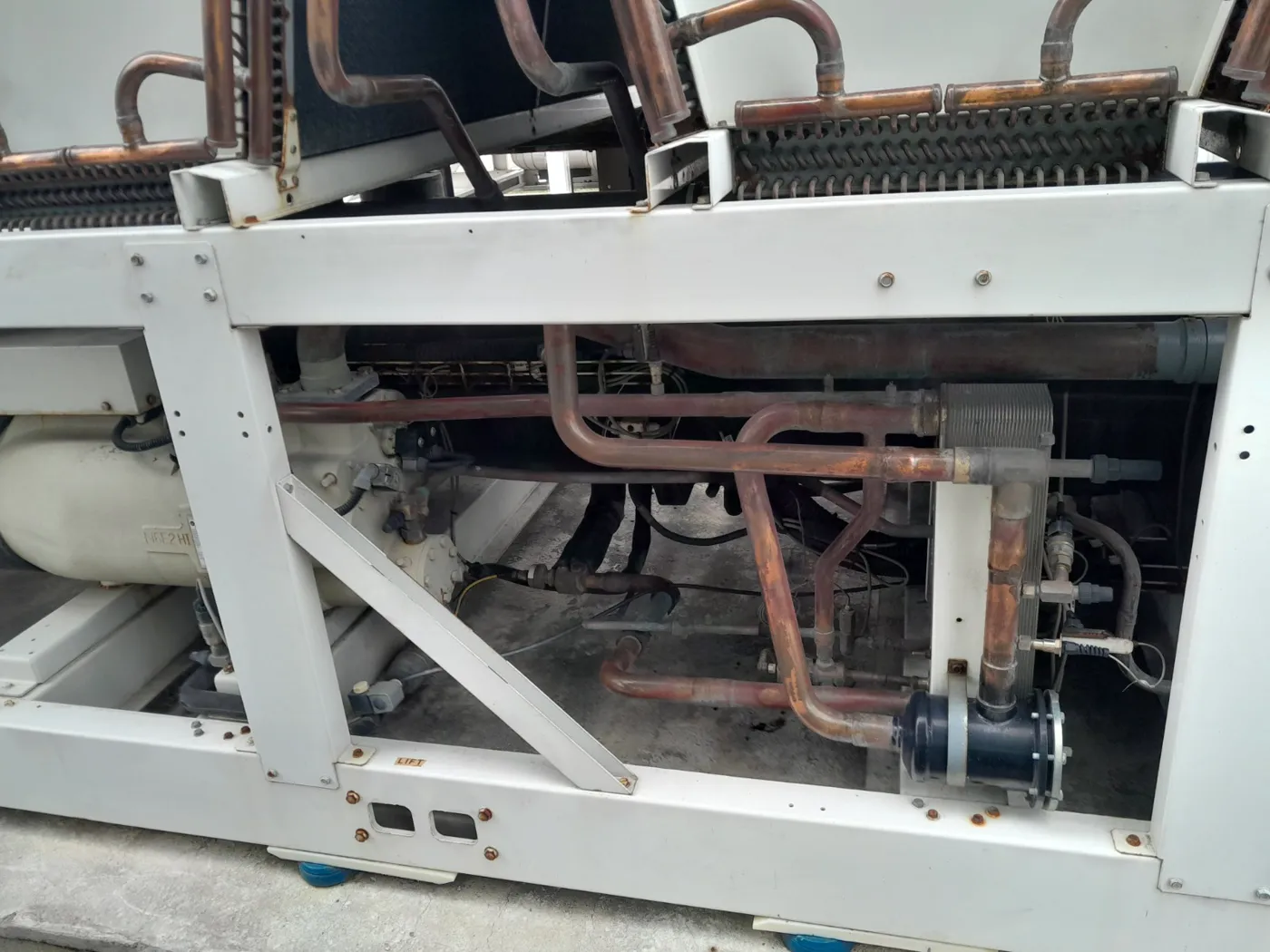 Chiller com tampa aberta expondo compressor e circuito frigorífico durante manutenção